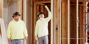 Two technicians installing insulation in a new construction home.