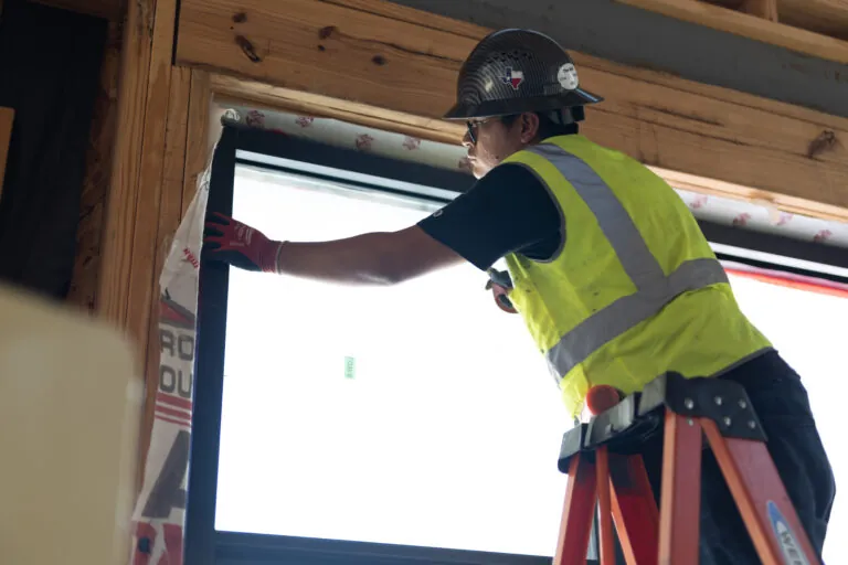 Man installing new vinyl windows on a new construction project