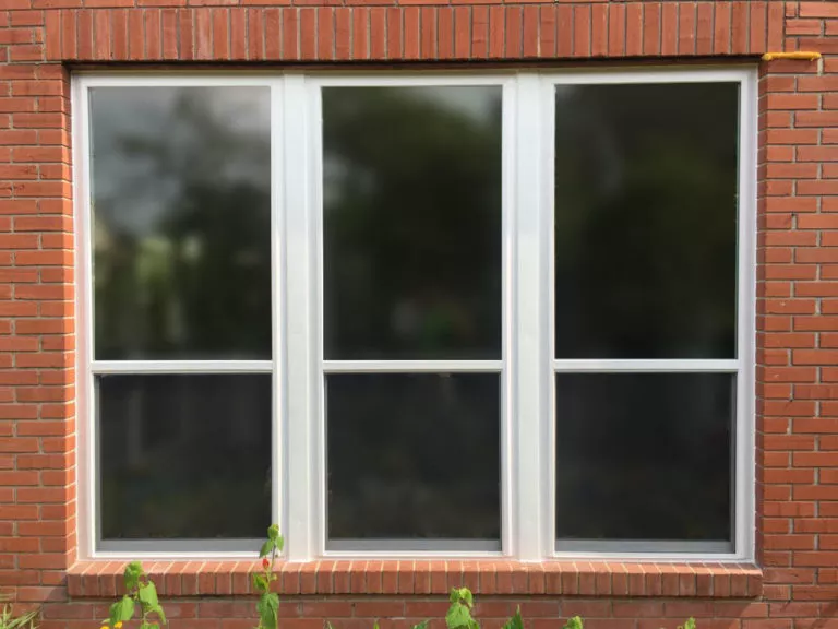 Exterior of a brick home in Nederland, TX with new vinyl windows installed