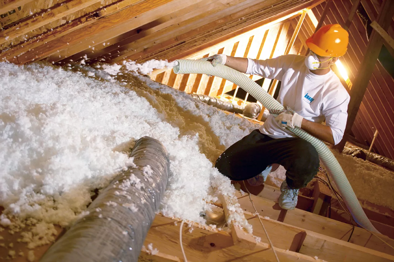 fiberglass insulation being blown into attic by an insulation contractor